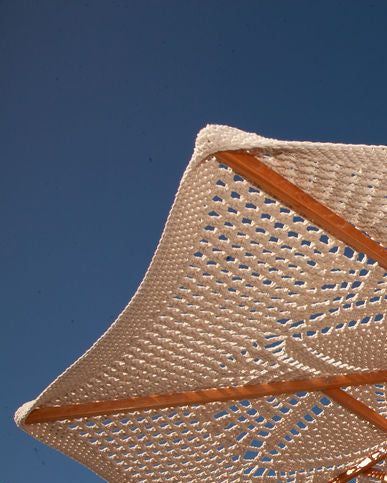 Hand crocheted parasol/umbrella with wooden pole with a clear blue sky